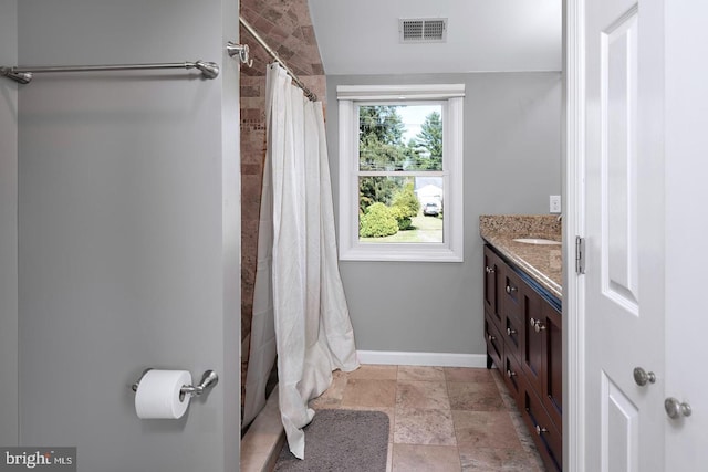 bathroom featuring visible vents, a shower with shower curtain, stone finish flooring, vanity, and baseboards