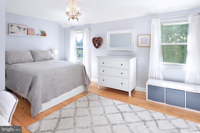 bedroom with light wood finished floors, baseboards, and a chandelier