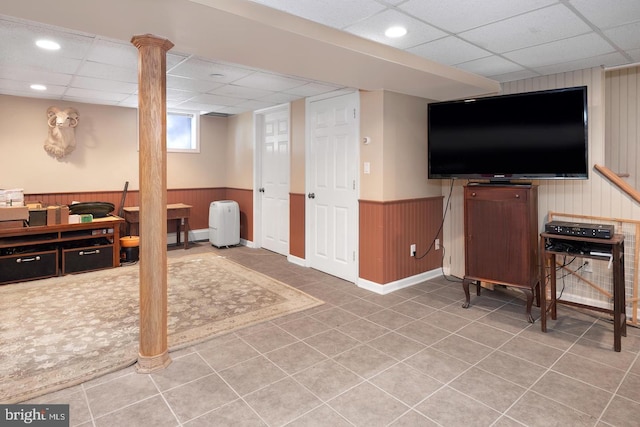 basement featuring a wainscoted wall, a drop ceiling, and wooden walls