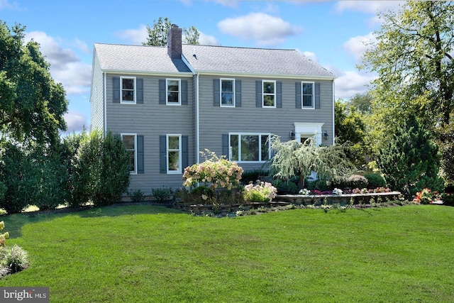 back of house featuring a chimney and a yard