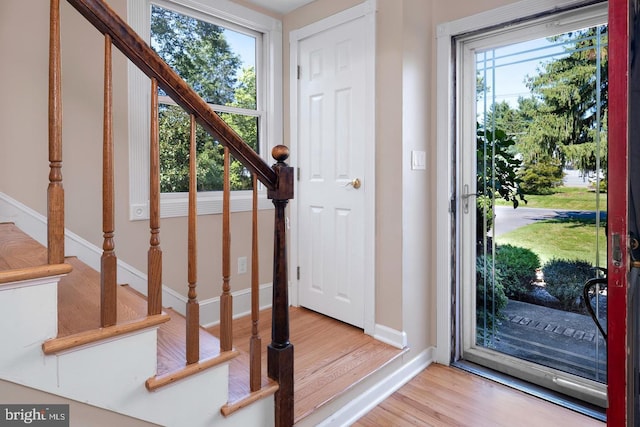 foyer entrance featuring light wood-style floors, baseboards, and stairs