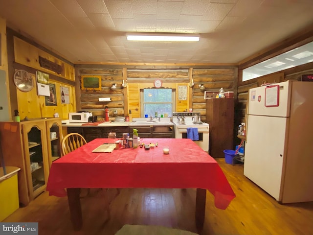 dining area featuring light wood-type flooring and log walls