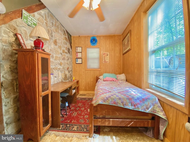 bedroom featuring ceiling fan and wooden walls