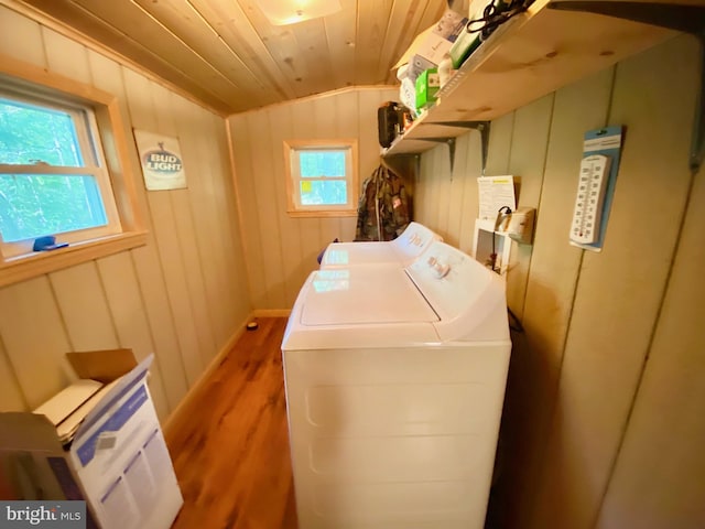 laundry area with laundry area, wooden walls, wood ceiling, wood finished floors, and washer and dryer