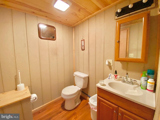 half bath featuring wooden ceiling, toilet, wood walls, wood finished floors, and vanity