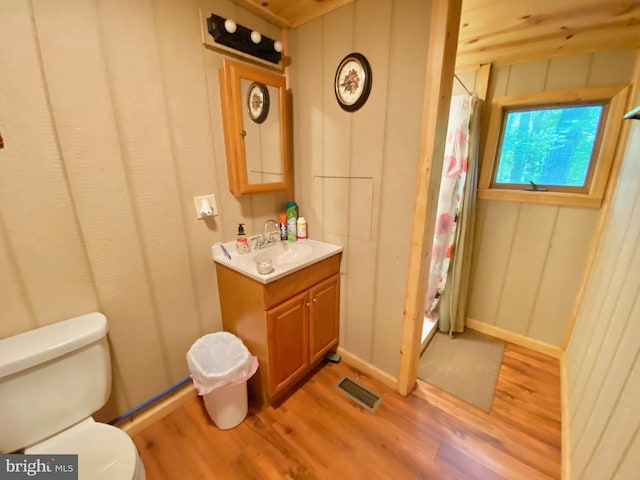 full bath with curtained shower, toilet, wood finished floors, vanity, and visible vents