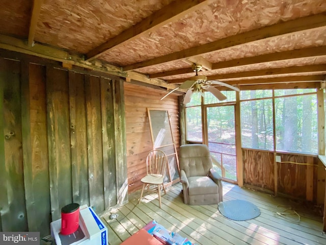 unfurnished sunroom featuring a ceiling fan and beamed ceiling