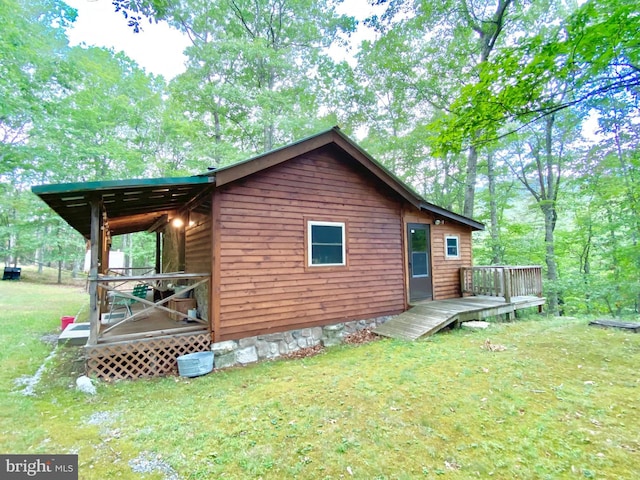 back of property featuring a deck and a lawn