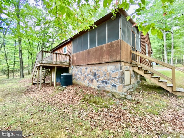 view of property exterior featuring a deck, a sunroom, central AC unit, and stairs