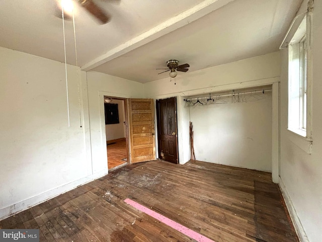 unfurnished bedroom featuring a ceiling fan, a closet, dark wood finished floors, and beamed ceiling