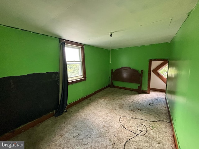 unfurnished bedroom with lofted ceiling, light carpet, and baseboards