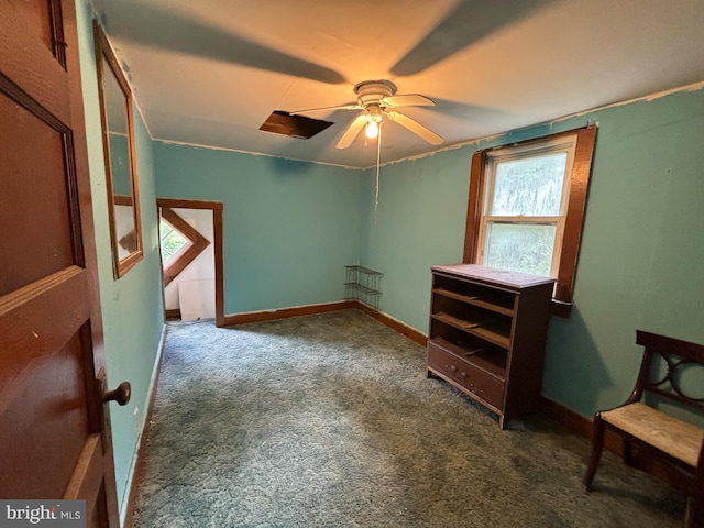 interior space featuring ceiling fan, dark colored carpet, and baseboards