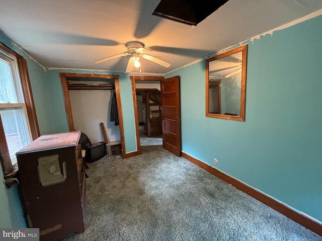 unfurnished bedroom featuring baseboards, dark carpet, and ceiling fan