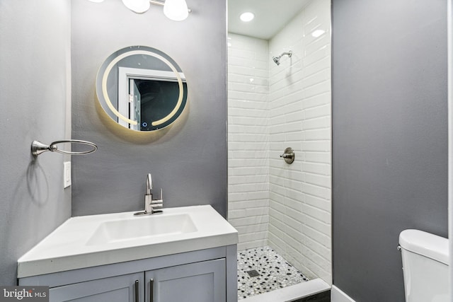 bathroom with toilet, vanity, and tiled shower