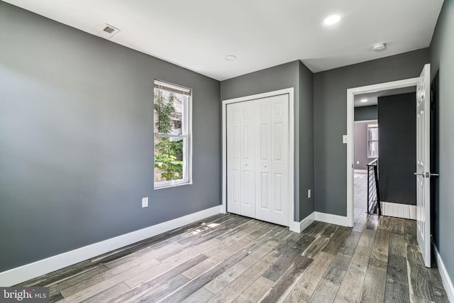 unfurnished bedroom featuring a closet and hardwood / wood-style flooring