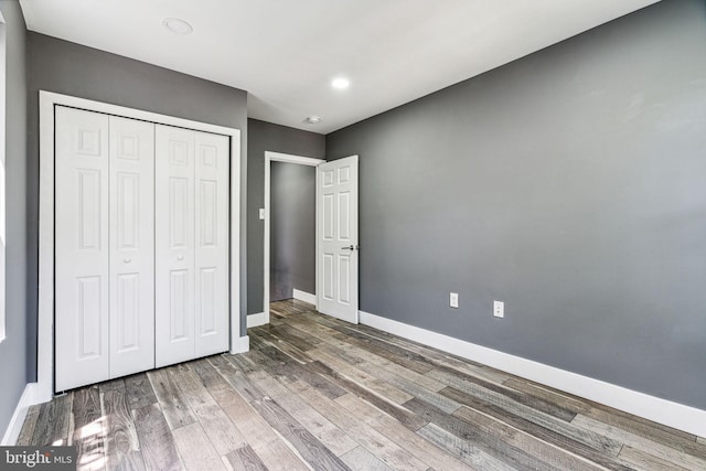 unfurnished bedroom with a closet and dark wood-type flooring