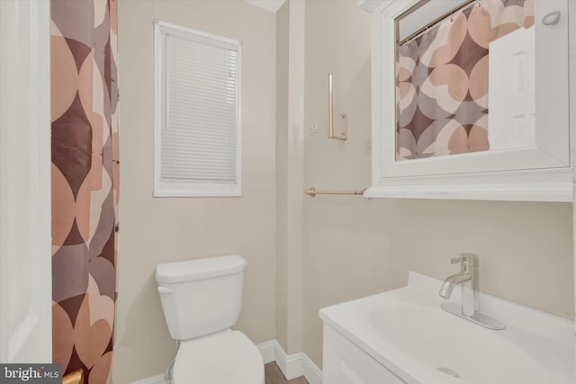 bathroom featuring toilet, vanity, and curtained shower