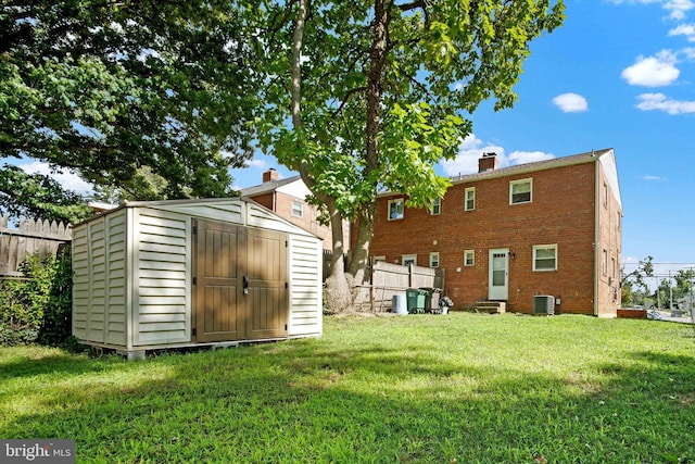 rear view of house featuring a storage unit, a yard, and central AC