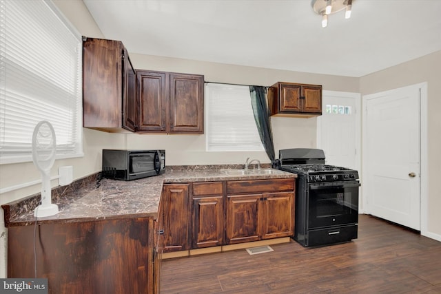 kitchen featuring dark brown cabinetry, sink, dark wood-type flooring, and black appliances