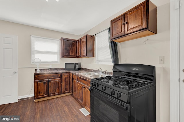 kitchen with dark hardwood / wood-style flooring, black appliances, and sink