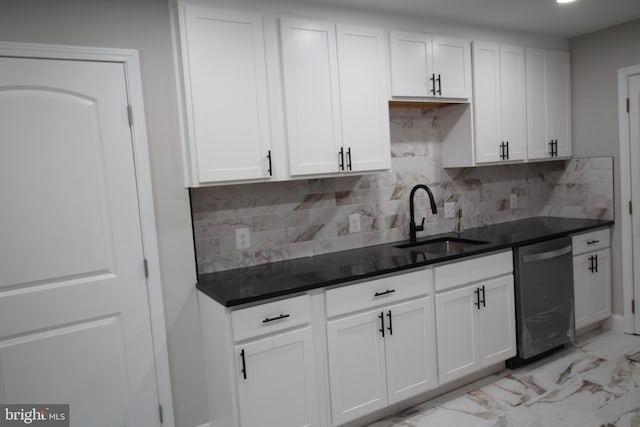 kitchen with dark countertops, a sink, white cabinetry, and stainless steel dishwasher