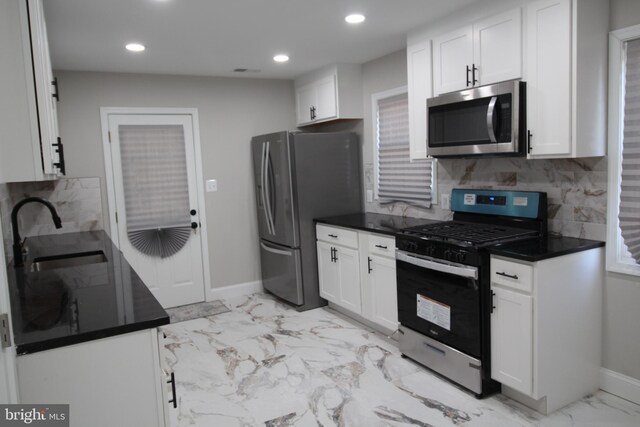 kitchen with tasteful backsplash, sink, stainless steel dishwasher, and white cabinetry