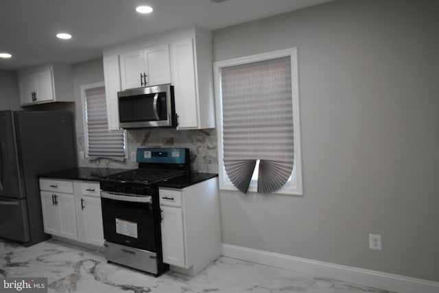 kitchen featuring stainless steel appliances, dark countertops, marble finish floor, and white cabinets