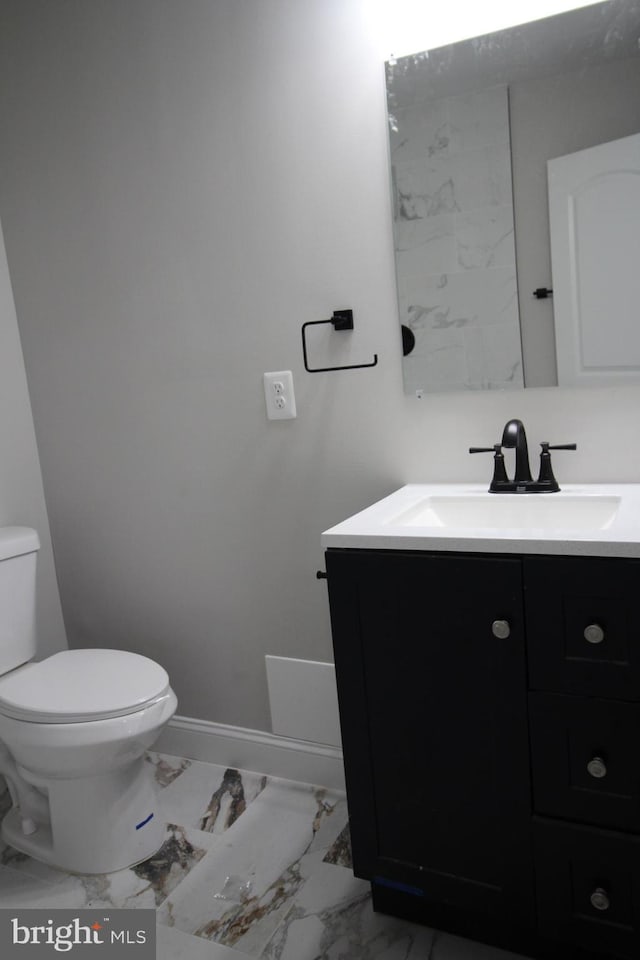 bathroom featuring toilet, marble finish floor, vanity, and baseboards