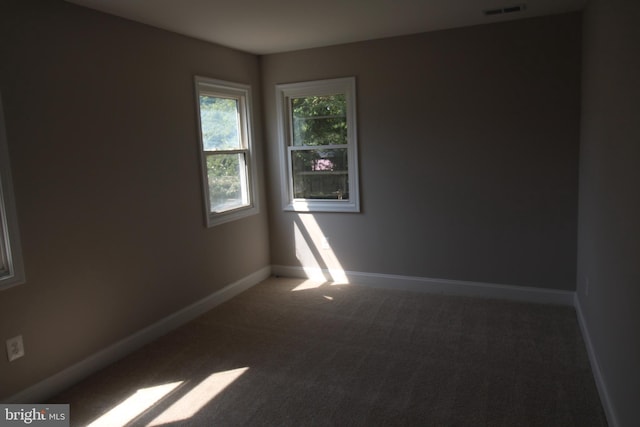 carpeted spare room featuring visible vents and baseboards