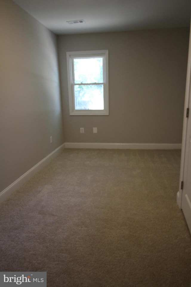 carpeted empty room featuring visible vents and baseboards