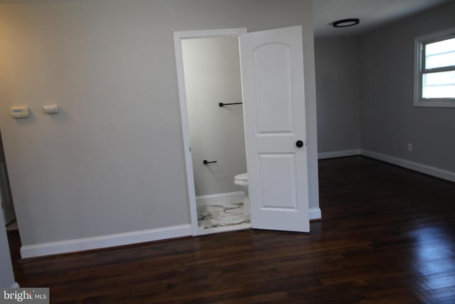 unfurnished bedroom with baseboards and dark wood finished floors