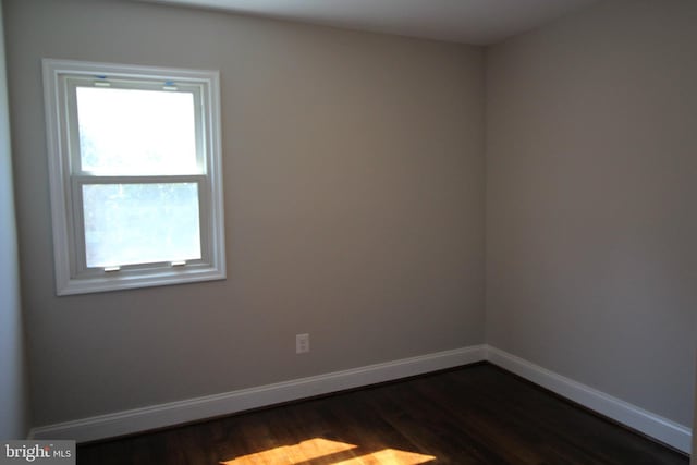 spare room with dark wood-style flooring and baseboards