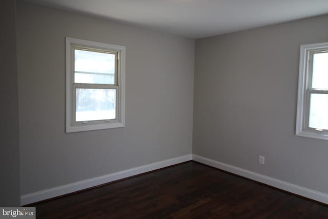 empty room with baseboards and dark wood-type flooring