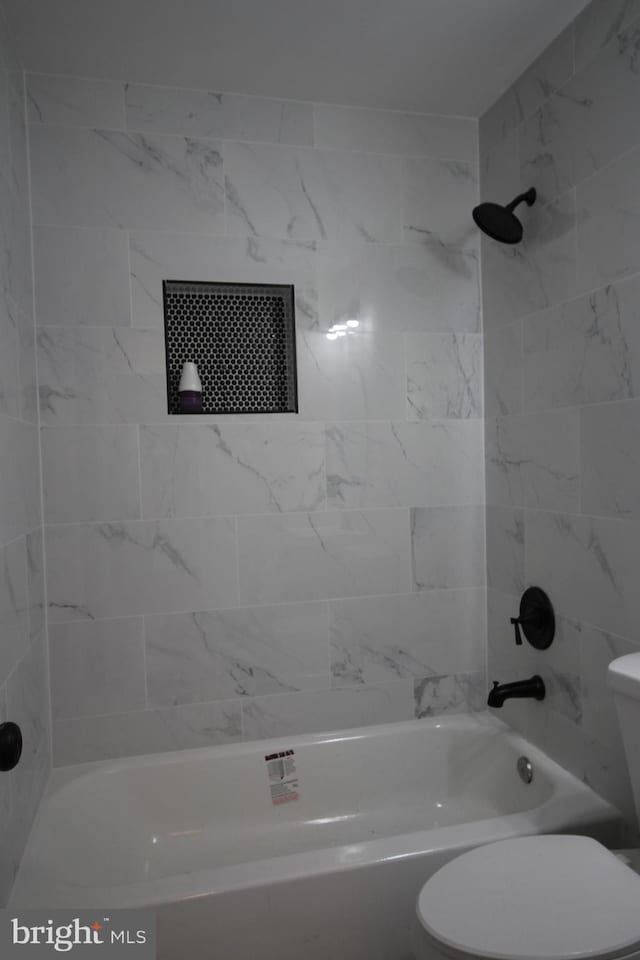 bathroom featuring tiled shower / bath and toilet