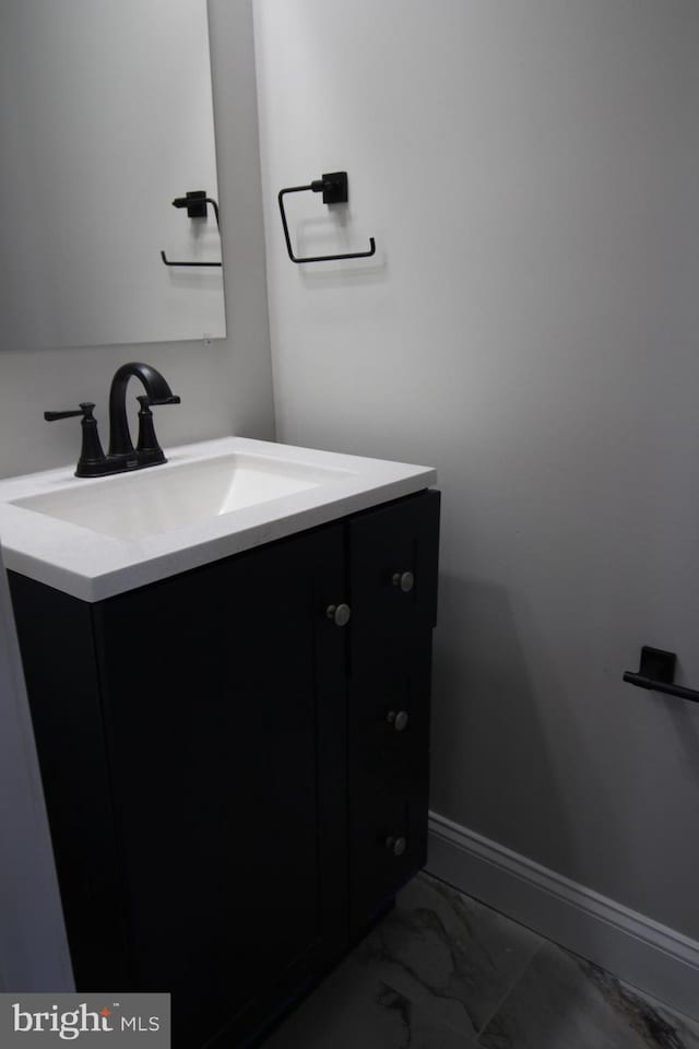 bathroom with marble finish floor, vanity, and baseboards