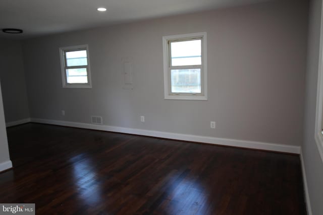 spare room featuring baseboards, visible vents, and dark wood-type flooring