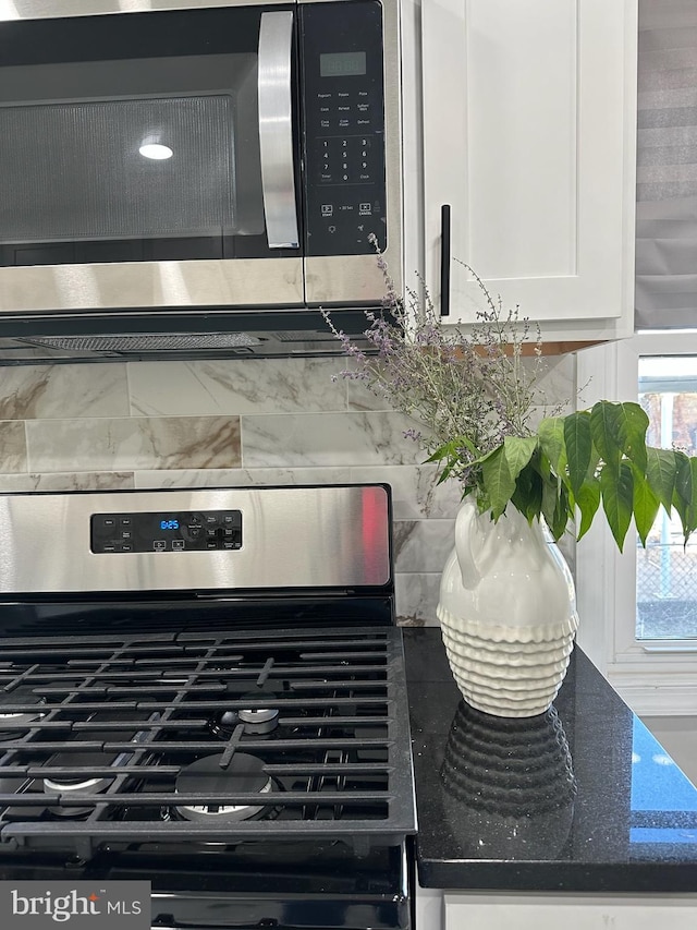 room details with stainless steel appliances, dark stone countertops, white cabinetry, and decorative backsplash