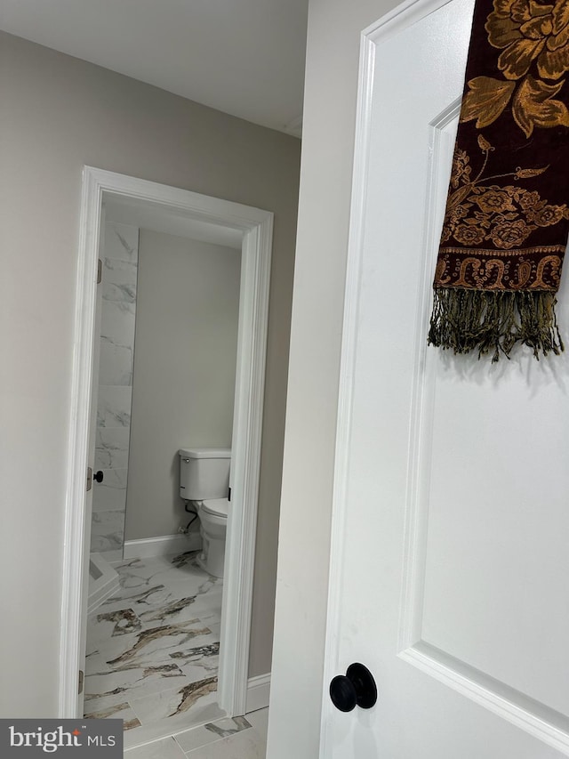 bathroom with marble finish floor, a shower, toilet, and baseboards