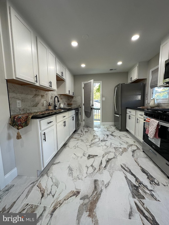 kitchen with dark countertops, stainless steel appliances, white cabinets, and decorative backsplash