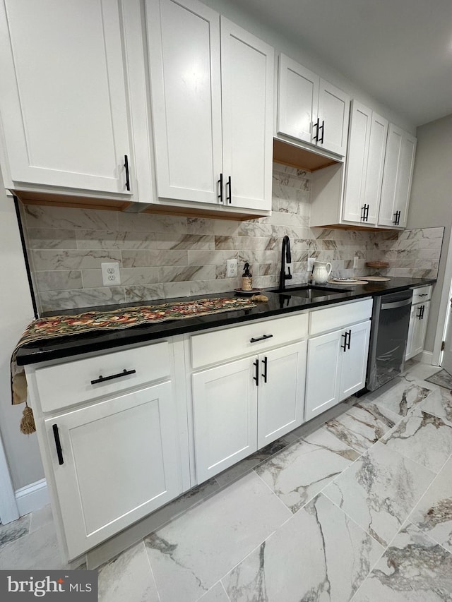 kitchen with backsplash, white cabinets, sink, and stainless steel dishwasher