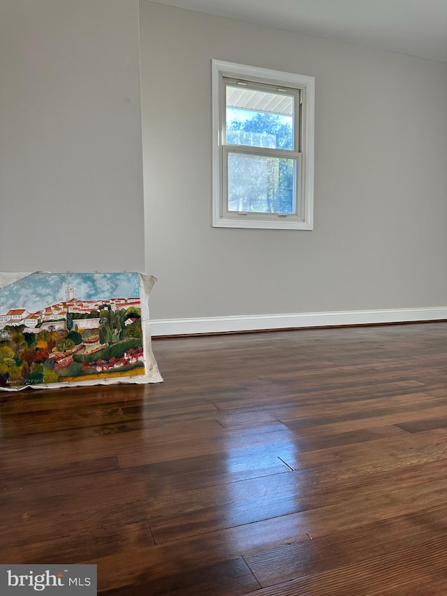 spare room featuring dark wood-style flooring and baseboards