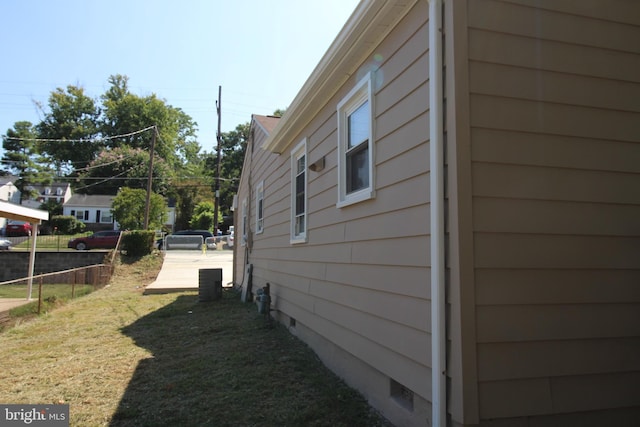 view of side of property with crawl space, fence, and a lawn