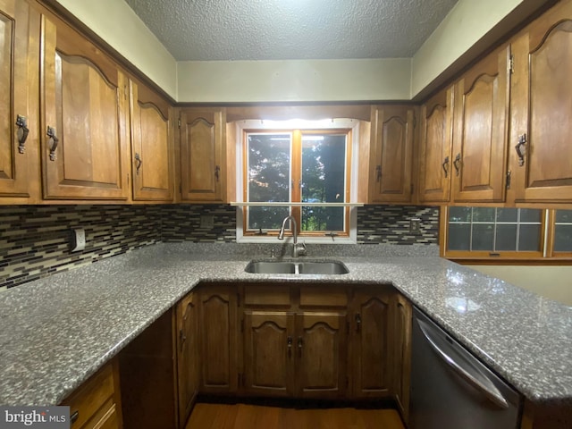 kitchen featuring dishwasher, a textured ceiling, sink, decorative backsplash, and dark hardwood / wood-style flooring