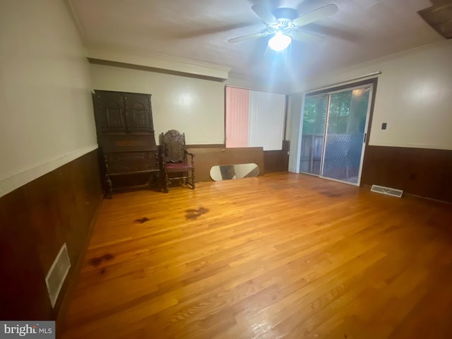 interior space with ceiling fan, hardwood / wood-style flooring, and wood walls