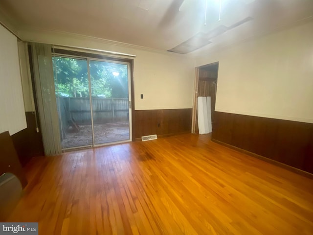 spare room featuring light wood-type flooring, wood walls, and ceiling fan