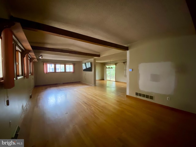 unfurnished living room with light wood-type flooring and lofted ceiling with beams