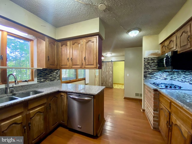 kitchen with appliances with stainless steel finishes, light hardwood / wood-style floors, kitchen peninsula, and a healthy amount of sunlight