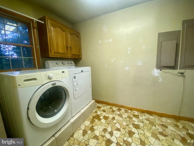 laundry area featuring electric panel, washer and dryer, and cabinets