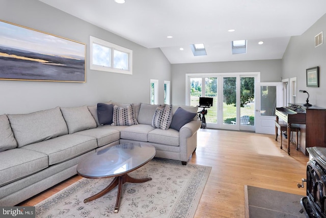 living room featuring high vaulted ceiling and light hardwood / wood-style flooring