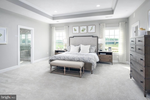 bedroom with light carpet, connected bathroom, a tray ceiling, and crown molding